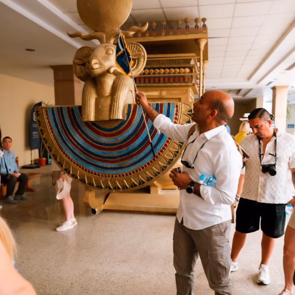 Tour guide explaining ancient Egyptian ram-headed statue to travelers inside museum