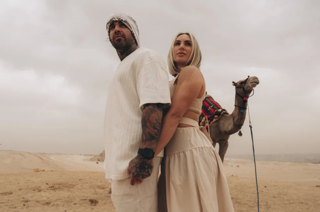 casal a posar com um camelo perto das Pirâmides de Gizé