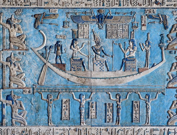 Detailed ancient Egyptian blue astronomical relief featuring gods on a solar barque, a historic Egypt travel site.