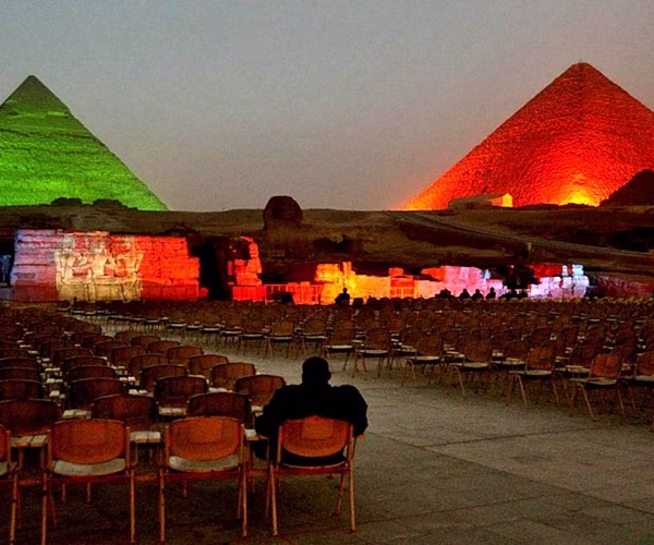The Giza Pyramids lit with green and red lights during a night sound and light show on an Egypt travel tour.