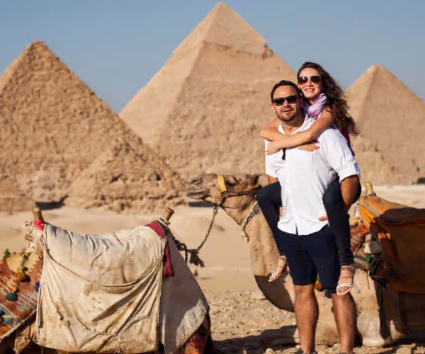 A man holds his lover in front of the scenic view of the Giza Pyramids