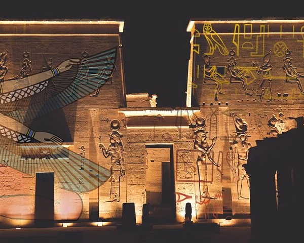 Ancient Egyptian temple facade with colorful modern light projections of gods and symbols, a unique Egypt travel show.