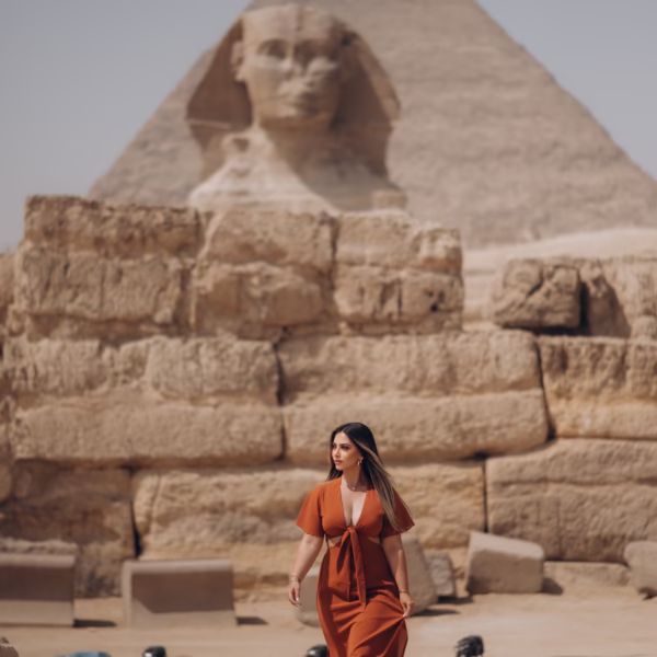Tourist posing at the Sphinx with the Great Pyramid of Giza in Egypt