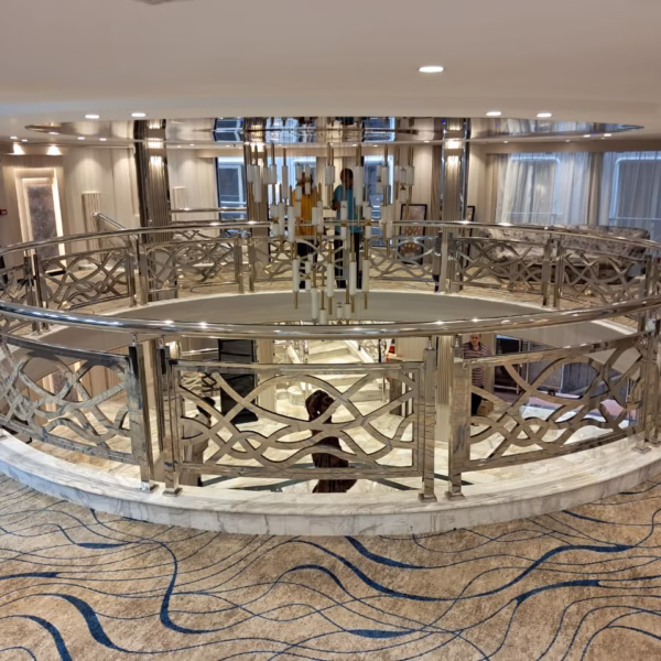 Circular mezzanine on a luxury Nile cruise featuring silver railings, a grand chandelier, and wave-patterned carpets.