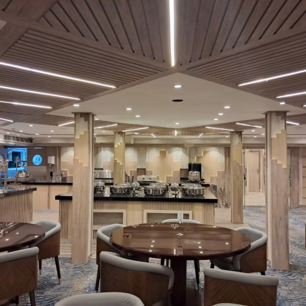 Modern Nile cruise restaurant with wood-slat ceilings, round dining tables, and a gourmet buffet for Egypt travelers.