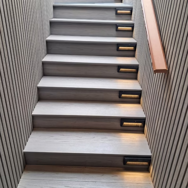 A modern outdoor staircase on a Nile cruise ship featuring light grey wood-textured steps with integrated LED safety lighting and sleek vertical-slat wall paneling.