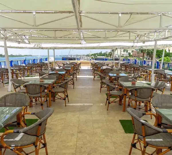 Shaded sun deck cafe on a Nile cruise ship with outdoor tables and river views for a luxury Egypt travel tour.