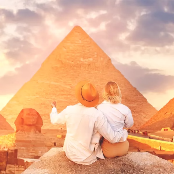 A couple sitting at the Giza Plateau watching the Great Pyramids and the Great Sphinx of Giza